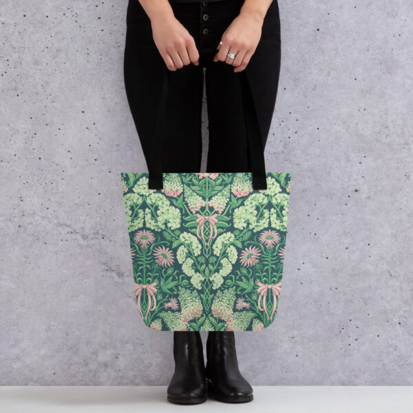 Pretty in Pinky tote carried by its handles against a concrete wall, full hydrangea print visible.