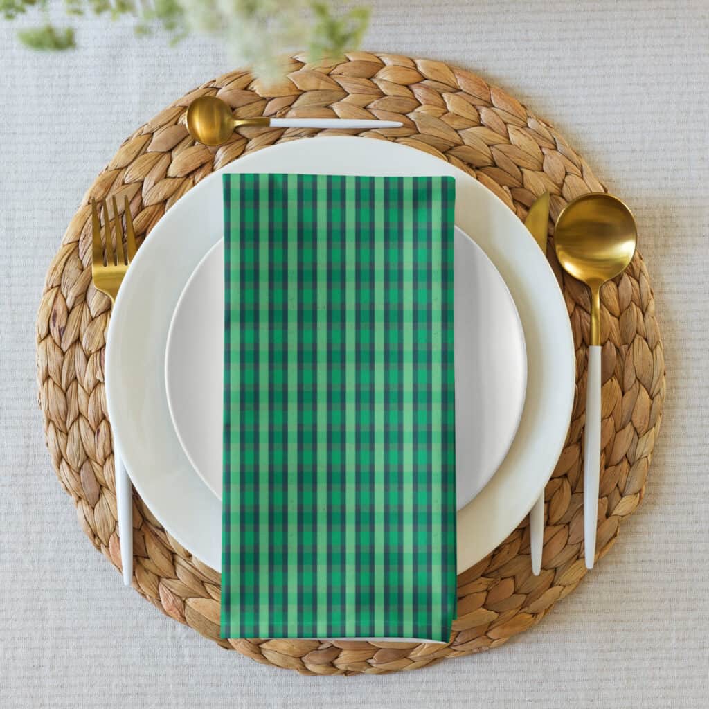 Napkin folded on a stacked plate setting with gold flatware, plaid print visible.