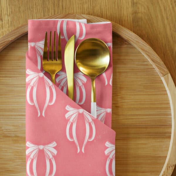 Napkin folded with gold flatware tucked inside, on a wood charger.