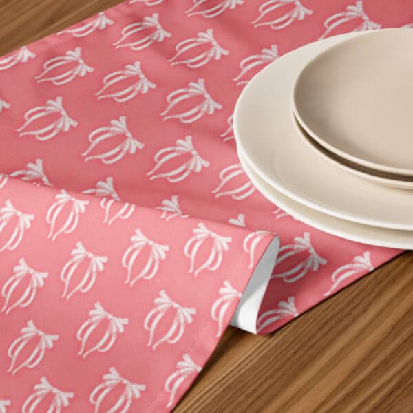 Pretty in Pinky Ribbons table runner styled with plates on a wood table, close-up of the bow print.
