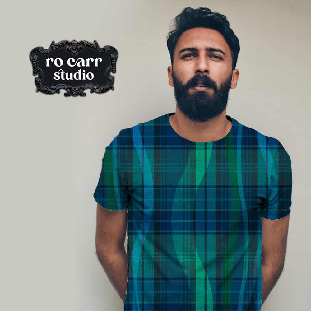 Bearded man wearing tee printed with "Breaking Plaid" pattern in navy and green.