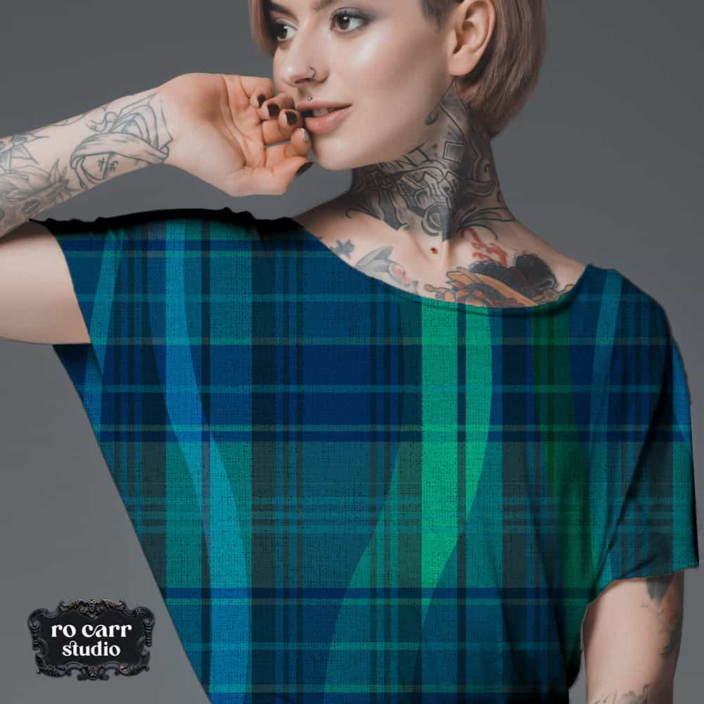Young woman with tattoos wearing a tshirt printed with Breaking Plaid in blue and green.