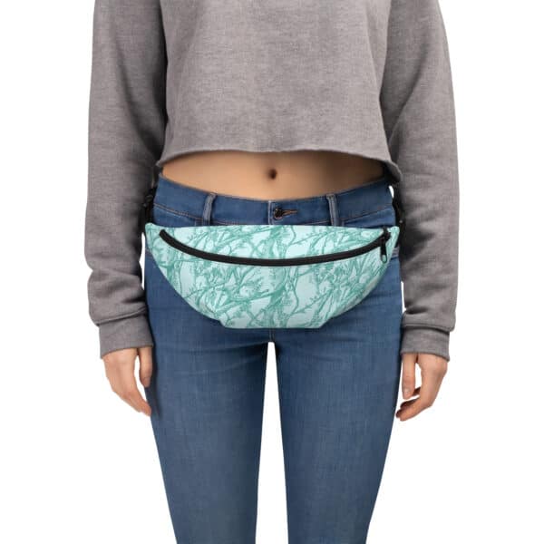 Close up of a woman wearing a fanny pack printed with Toile de Vie in aqua, slung across her middle.
