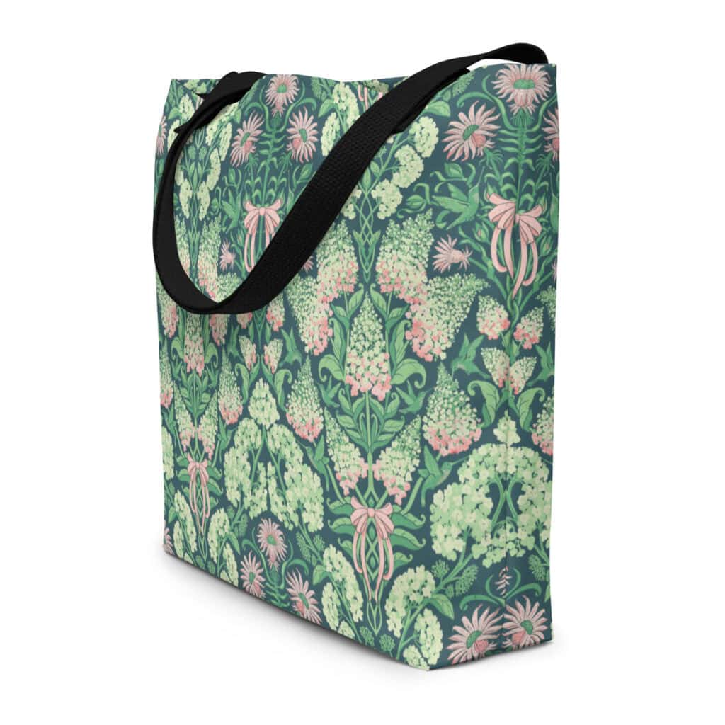 Three-quarter view of the pink and green hydrangea, bee balm, and ribbon print on a dark teal tote, with a black cloth handle.
