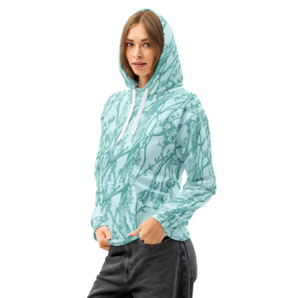 Cotton knit unisex hoodie printed in Toile de Vie in aqua, worn by a young woman, shown with the hood up.