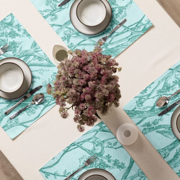 Set of four placemats printed with Toile de Vie design in aqua, shown from above on a table set for four.