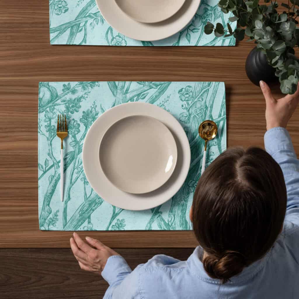 Placemat setting shown from above, including a woman setting down a vase.