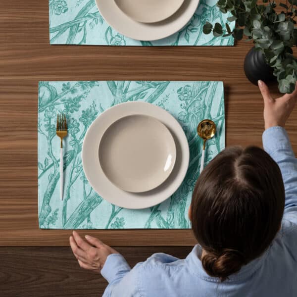 Placemat setting shown from above, including a woman setting down a vase.