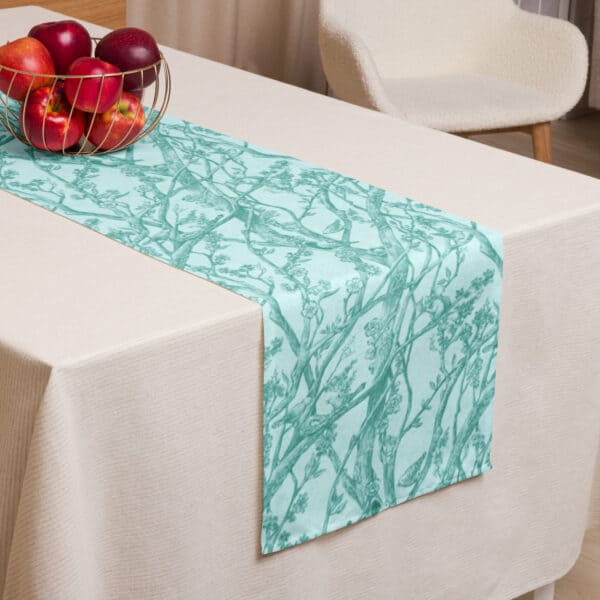 Table runner shown at edge of table, laid atop a white tablecloth.