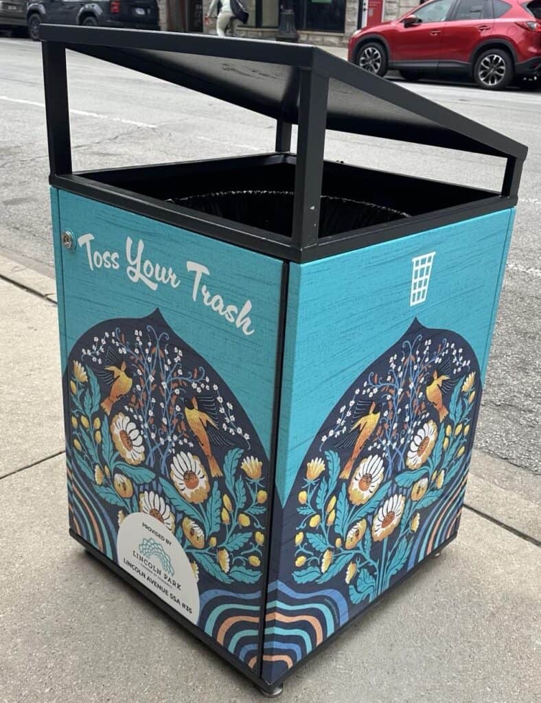 Citibin on a Chicago sidewalk wrapped in a hand-drawn illustration of buttercups and Baltimore Orioles on a dark arched panel, set against a turquoise background.