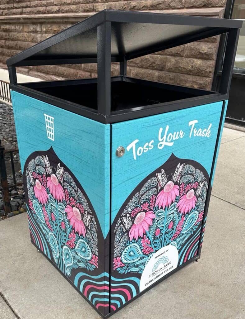 Citibin on a Chicago sidewalk wrapped in a hand-drawn illustration of pink coneflowers, butterflies, and paisley leaves on a dark arched panel, set against a turquoise background.