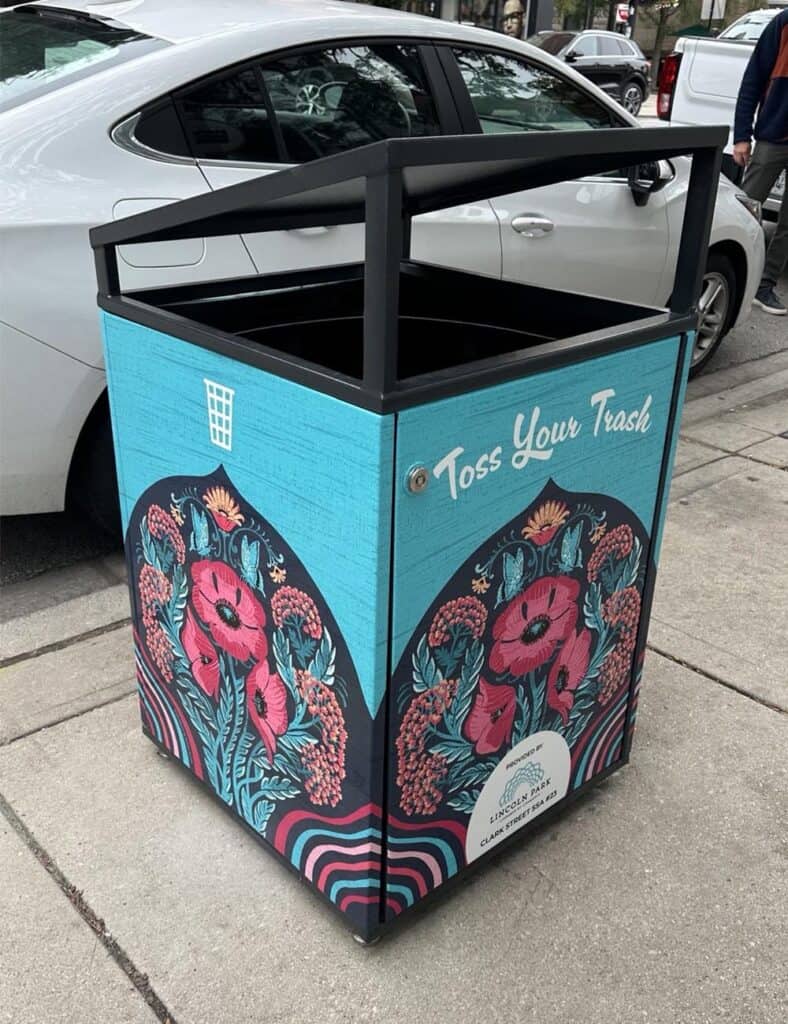 Citibin on a Chicago sidewalk wrapped in a hand-drawn illustration of red poppies, blue butterflies and teal foliage on a dark arched panel, set against a turquoise background.