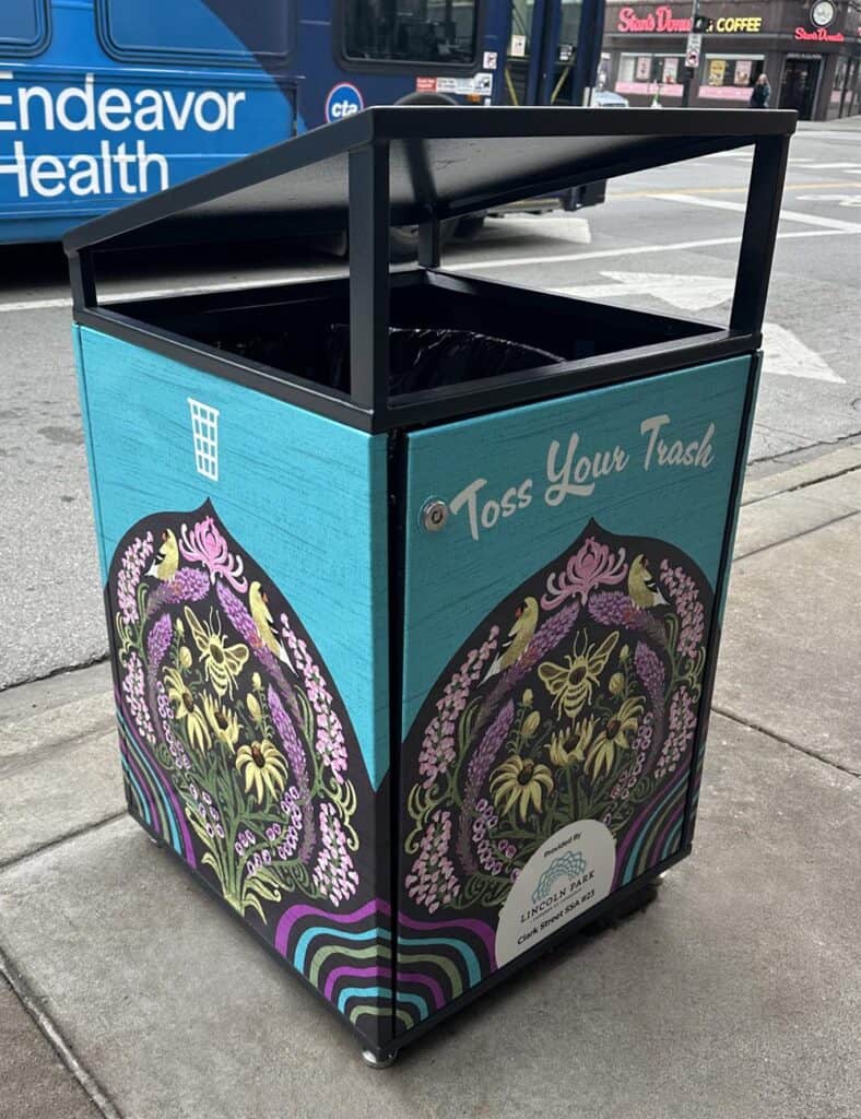 Citibin on a Chicago sidewalk wrapped in a hand-drawn illustration of black-eyed Susans, purple blooms, goldfinches and bees on a dark arched panel, set against a turquoise background.