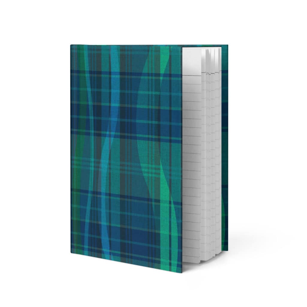 Breaking Plaid hardcover journal standing upright, showing the front cover's teal, blue, and green plaid print broken by flowing wave shapes, and the edges of the lined pages.