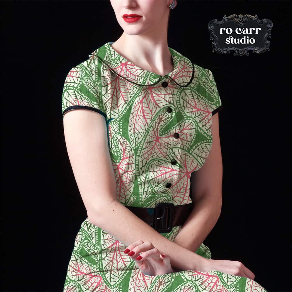 A woman in a vintage-style dress with a Peter Pan collar and black belt, made from block print caladium fabric.