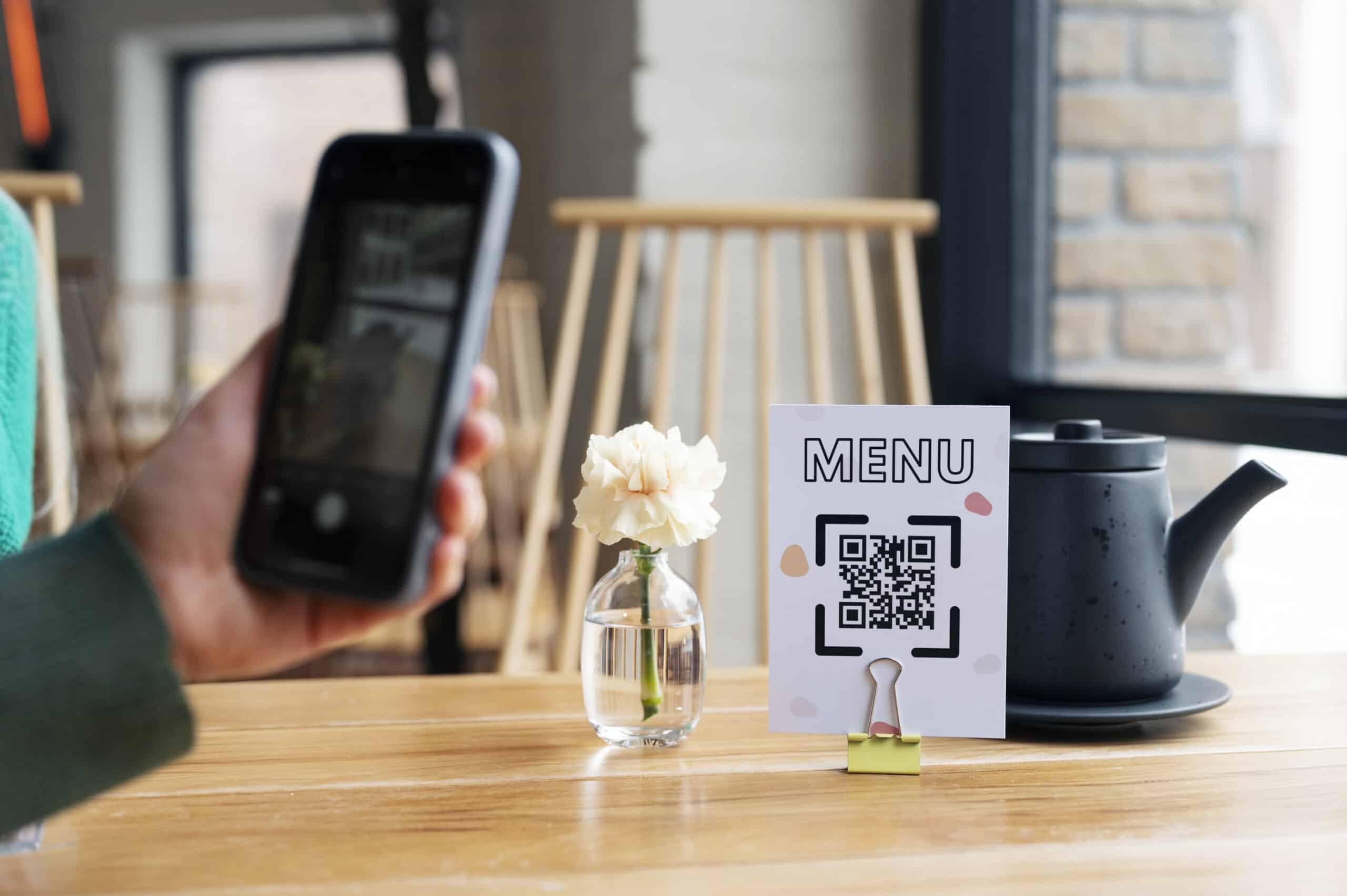 Hand scanning QR code at restaurant