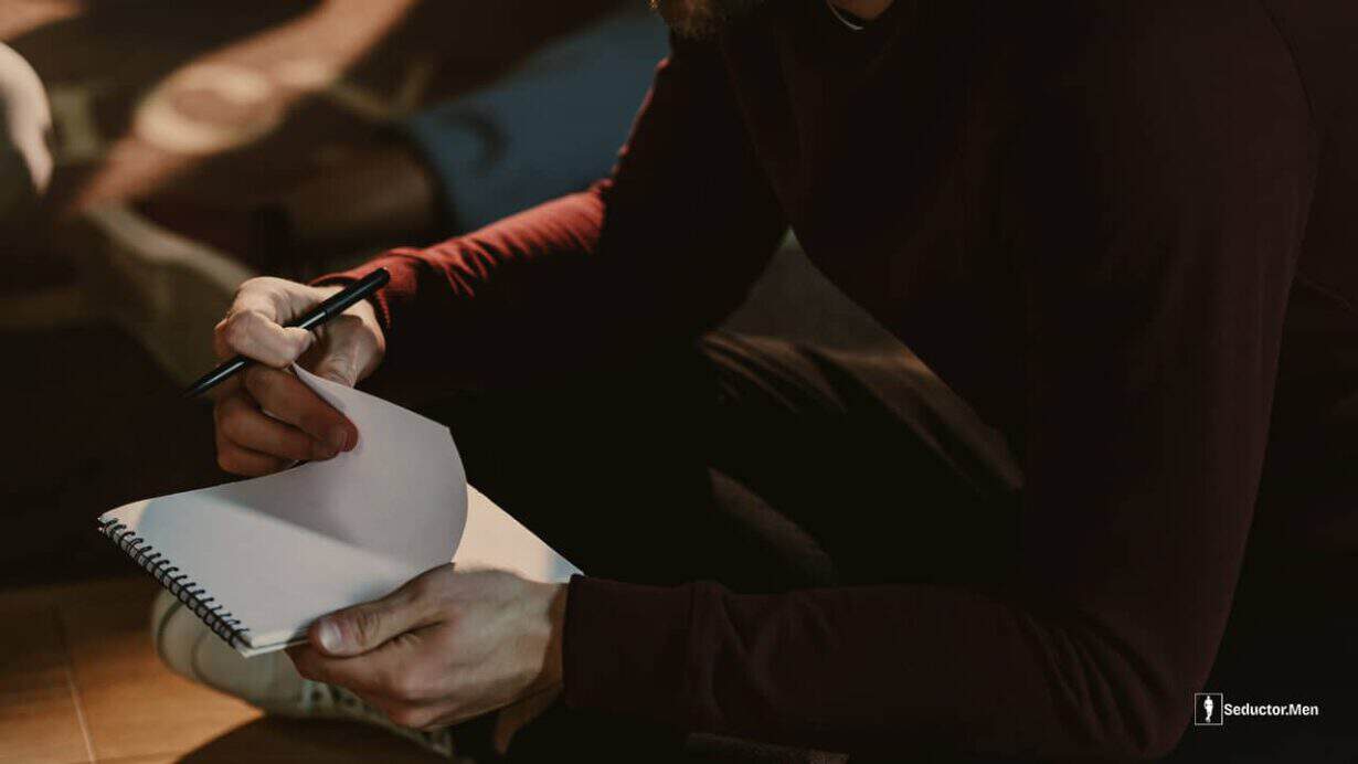 Hombre escribiendo en un cuaderno sus reglas de la seducción