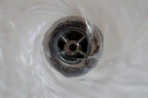 Close-up of water swirling around a metal sink drain, highlighting the importance of proactive care for worry-free home plumbing.