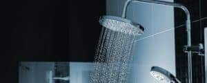 A gentle stream flows from a modern showerhead in a stylish, tiled bathroom—enjoy comfort with trusted local water heater experts.
