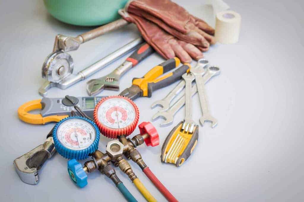 Essential HVAC tools—wrenches, pliers, gauge manifold, gloves, and tape—arranged neatly, ready for reliable local service.