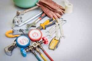 Essential HVAC tools—wrenches, pliers, gauge manifold, gloves, and tape—arranged neatly, ready for reliable local service.