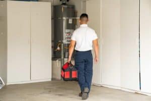 A friendly Service Champions technician approaches a water heater in a Downey garage, ready to provide expert, reliable service.
