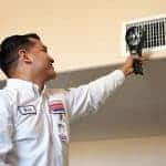 A friendly technician in uniform inspects an air vent with care, ensuring top comfort and quality for your Southern California home.