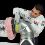 A friendly technician expertly works on insulated air ducts using the PureFlow Process, ensuring dependable home comfort in SoCal.