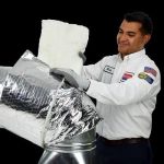 A friendly Service Champions technician expertly insulates an air duct, using the trusted PureFlow Process to ensure home comfort.