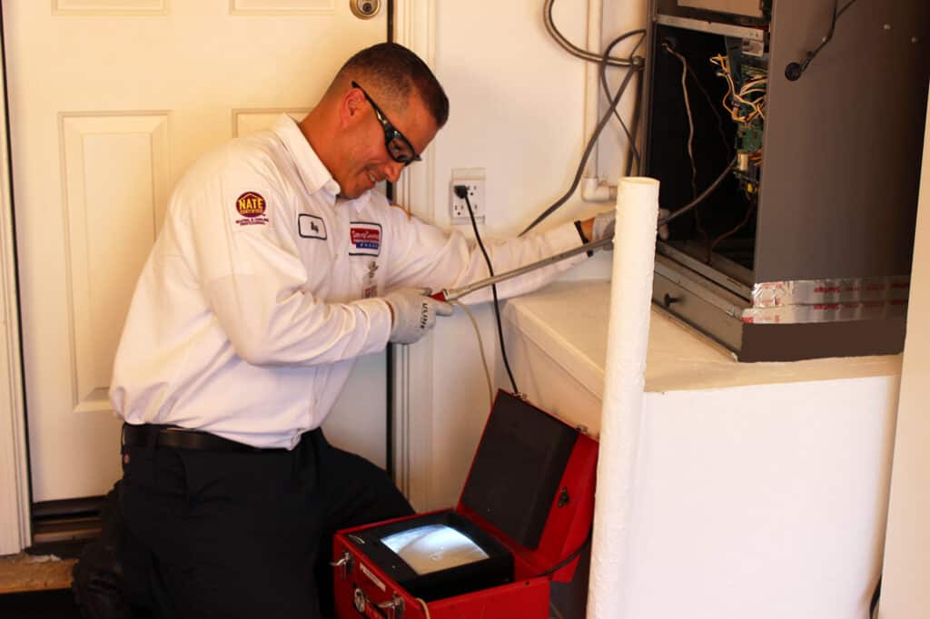 A friendly Service Champions expert inspects an HVAC unit for a fall furnace filter swap, ensuring your Southern California home’s comfort.