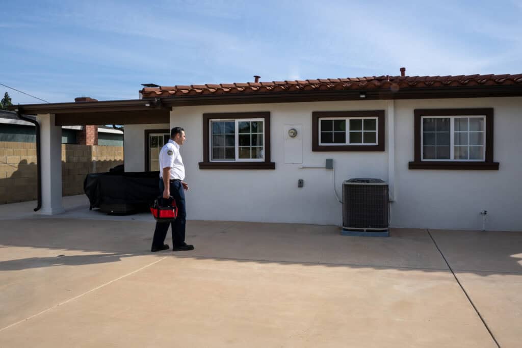 A Service Champions technician, ready with his tool bag, heads to a Southern California home for trusted summer maintenance service.