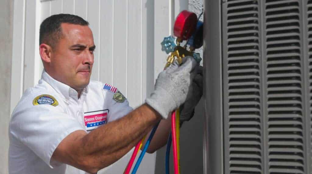 A friendly, uniformed Service Champions technician carefully adjusts gauges on an outdoor air conditioning system, wearing gloves and showing attentive focus. Their professionalism reflects Service Champions’ dedication to providing dependable, customer-focused HVAC services in Southern California—ensuring local homeowners experience comfort and peace of mind from a trusted home service expert.