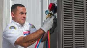 A friendly, uniformed Service Champions technician carefully adjusts gauges on an outdoor air conditioning system, wearing gloves and showing attentive focus. Their professionalism reflects Service Champions’ dedication to providing dependable, customer-focused HVAC services in Southern California—ensuring local homeowners experience comfort and peace of mind from a trusted home service expert.