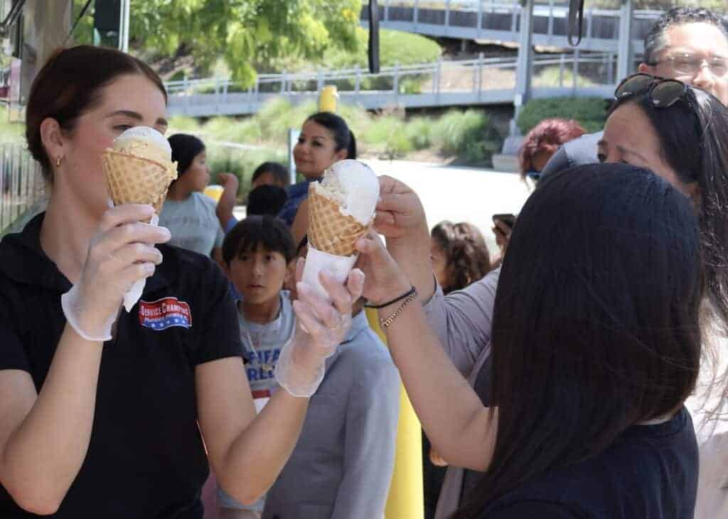 A friendly Service Champions team member, wearing gloves, serves complimentary ice cream waffle cones to community members waiting in line at an outdoor Anaheim event. This gesture reflects Service Champions’ dedication to dependable, customer-focused service as a trusted local expert in HVAC, plumbing, and drain solutions throughout Southern California.