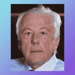 Unfocused elderly man with white hair and blue shirt, portrait, serious expression.