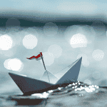 Paper boat floating on sparkling water