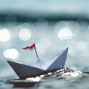 Paper boat floating on sparkling water