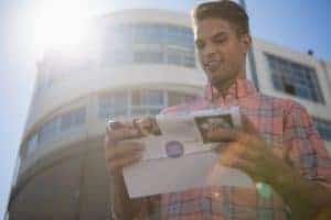 Bright young man reading direct mail envelope in urban setting for direct marketing.