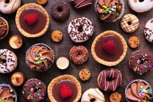 Colorful assortment of decorated cookies and cupcakes on dark surface.