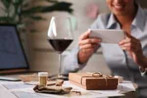 - Engaging woman using smartphone with direct mail marketing materials on table.
