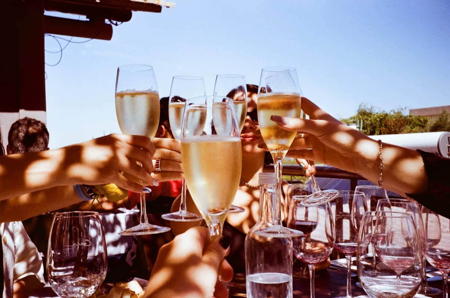 A group of people raise wine glasses together in a toast.