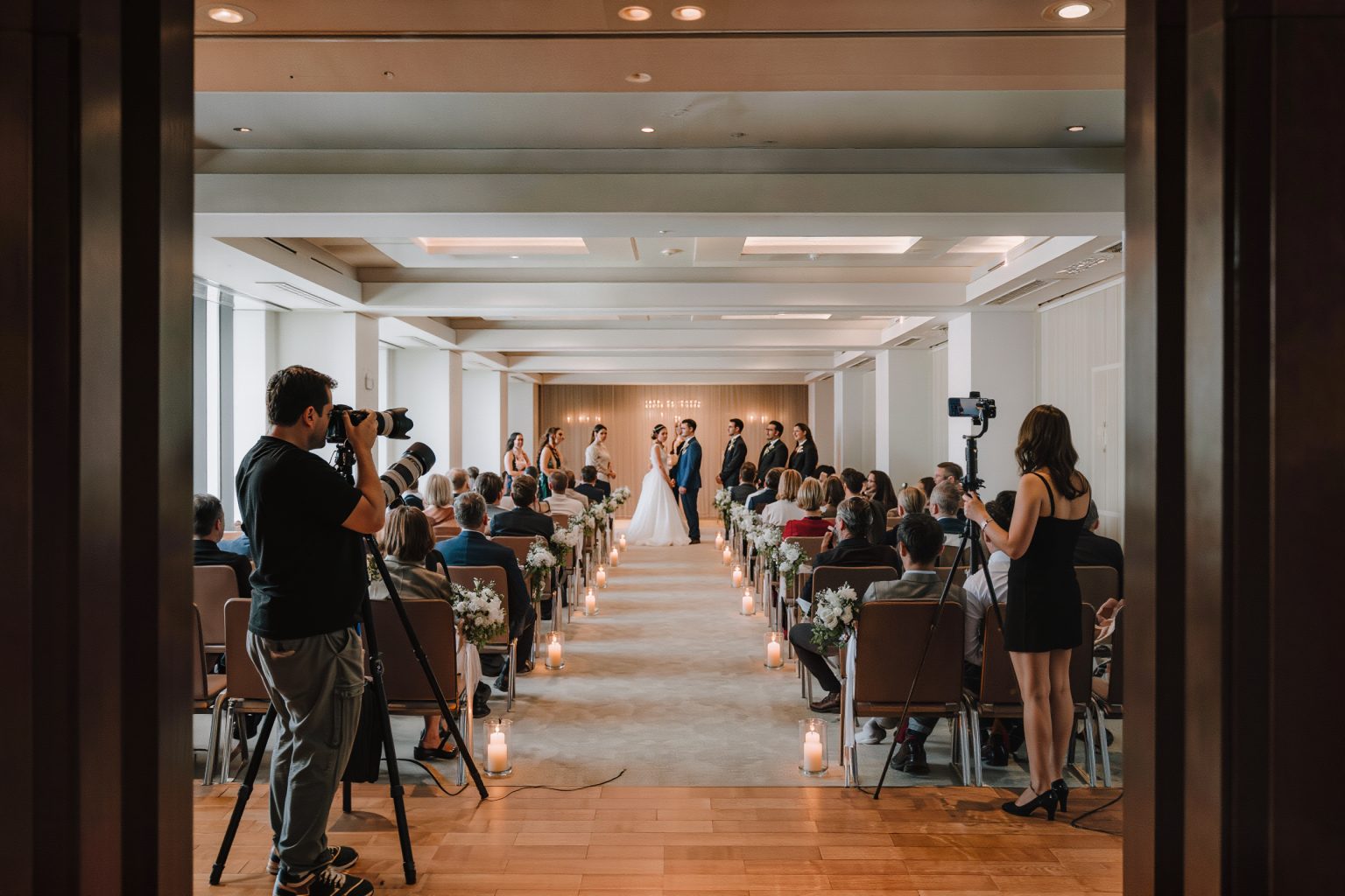 Wedding ceremony seen from behind the media line, where a photographer and content creator work without blocking guests