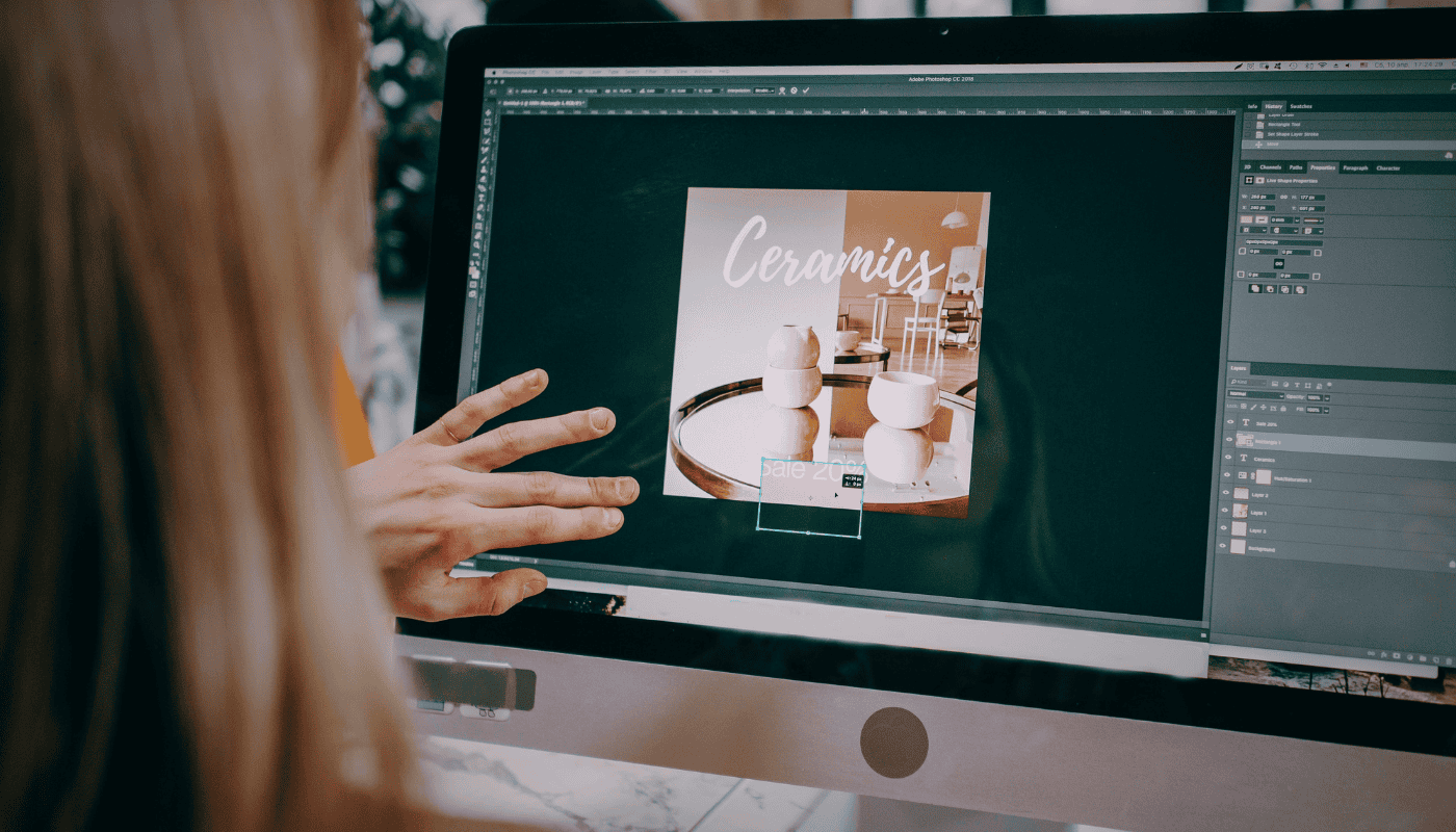 A designer working on a laptop with creative software visible on screen, illustrating the consolidation battle between Canva, Adobe and Figma for dominance over the creative workflow market.