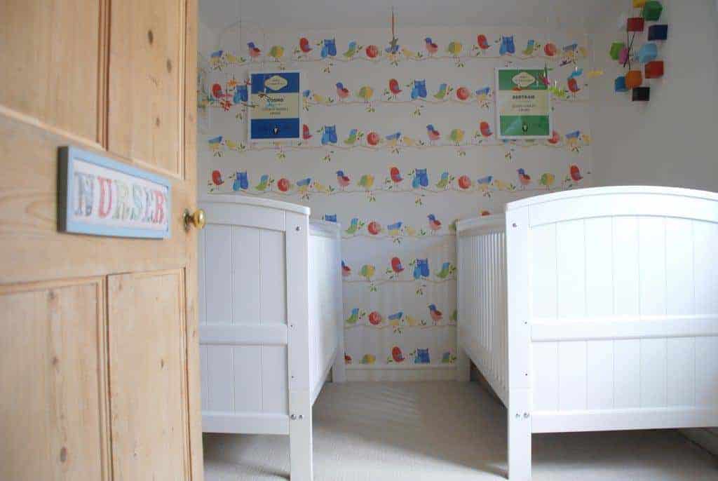 white wooden cribs in a twin nursery