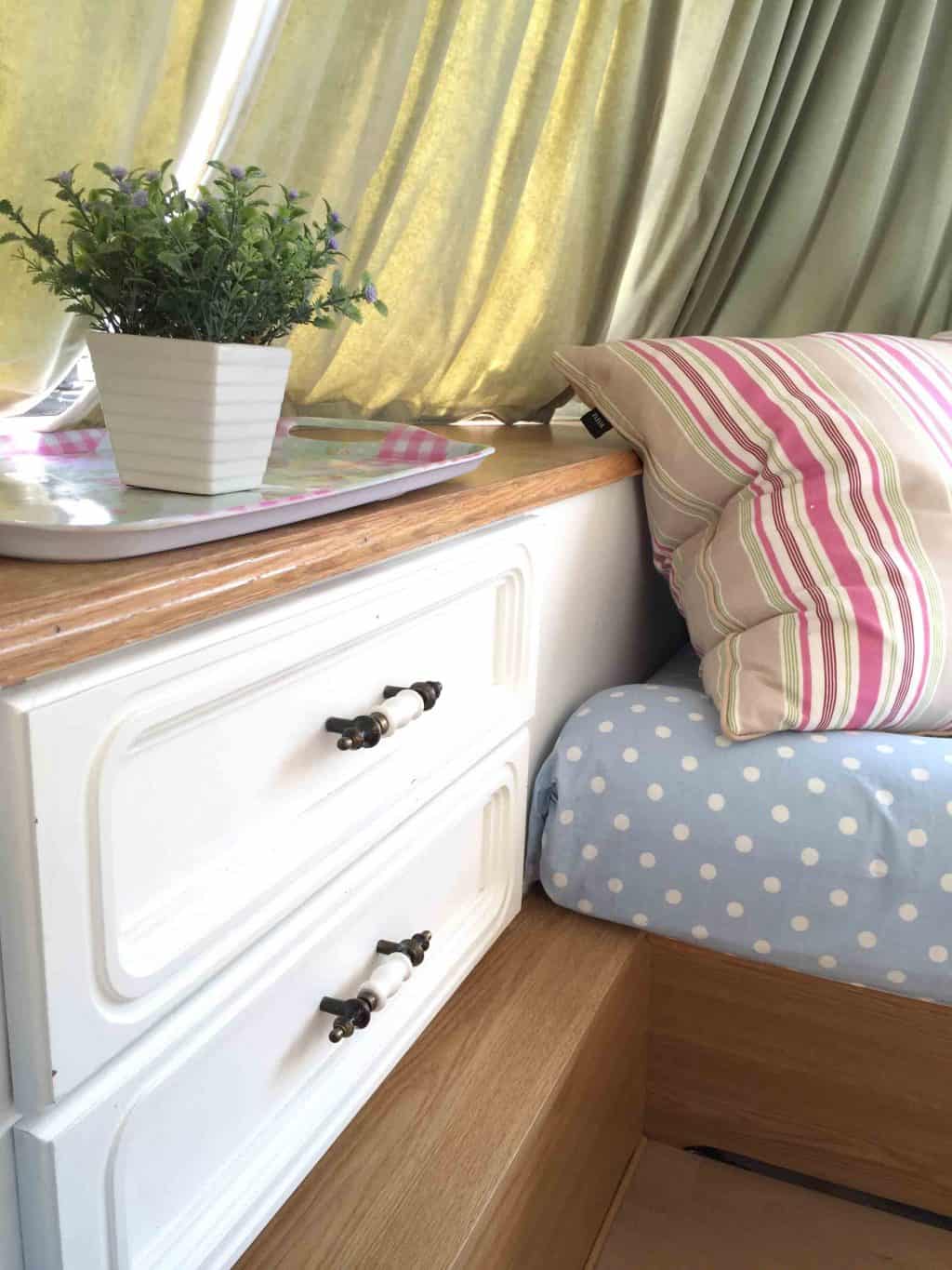 Close up of the drawer unit and shelf in Dolly the caravan; after it had been painted as part of my first caravan makeover. I kept the original green velvet curtains but covered the seats with blue polkadot fabric. More info on both of my caravan makeovers on the blog!