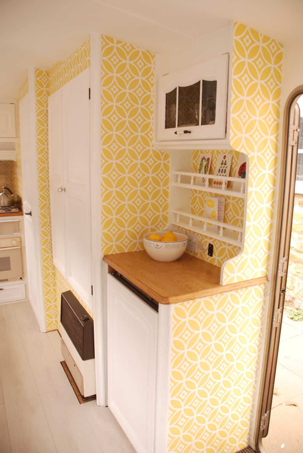 Caravan Renovation Project: After we'd carried out our restoration. Dolly looks fresh and bright with yellow wallpaper and white cabinetry.
