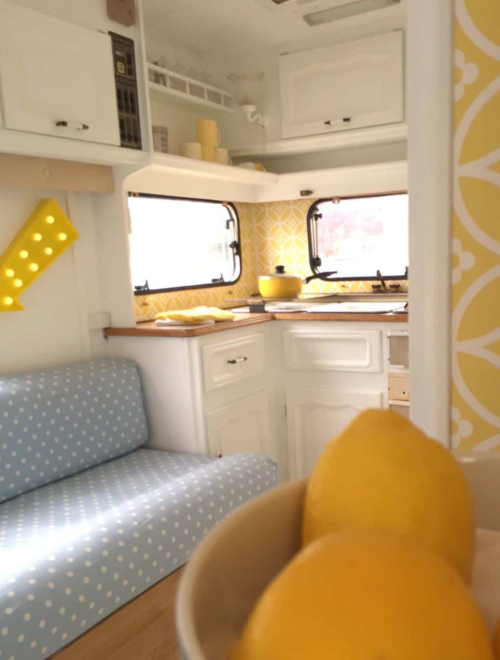 Caravan Renovation Project: After we'd carried out our restoration. Dolly looks fresh and bright with yellow wallpaper and blue and white polka dot seating in the lounge area.