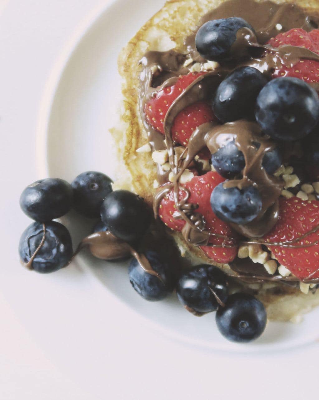 Eggless Pancake Recipe — pancakes with Nutella, blueberries, strawberries and chopped nuts