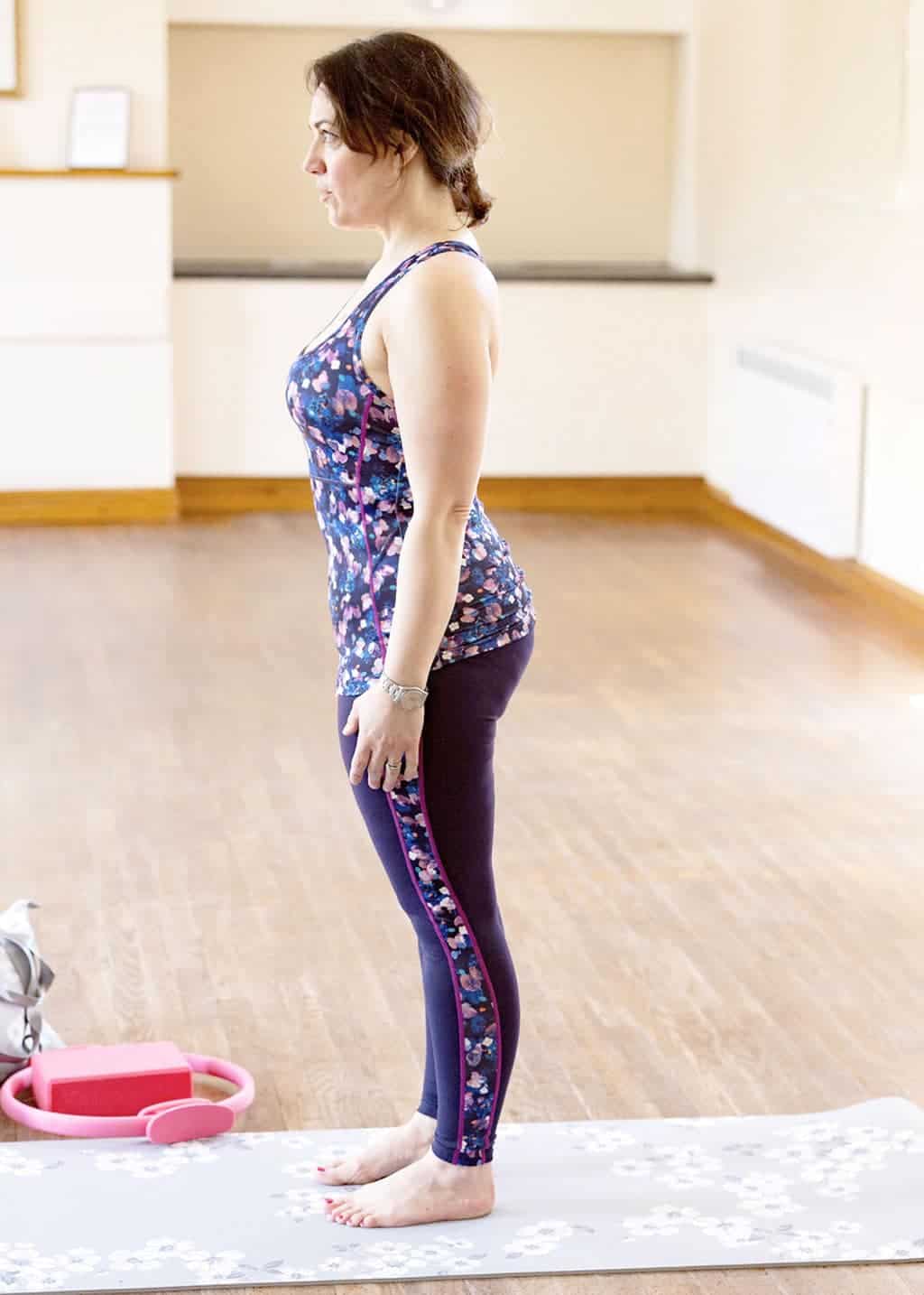 My Favourite 5 Pilates Moves — The Pilates Roll Down — Position 1 — Stand with feet hip distance apart, toes and hips pointing forward. Your shoulders should be back and down — but relaxed. Stand as though you're a skeleton hanging from the ceiling by a thread in a doctors office!!