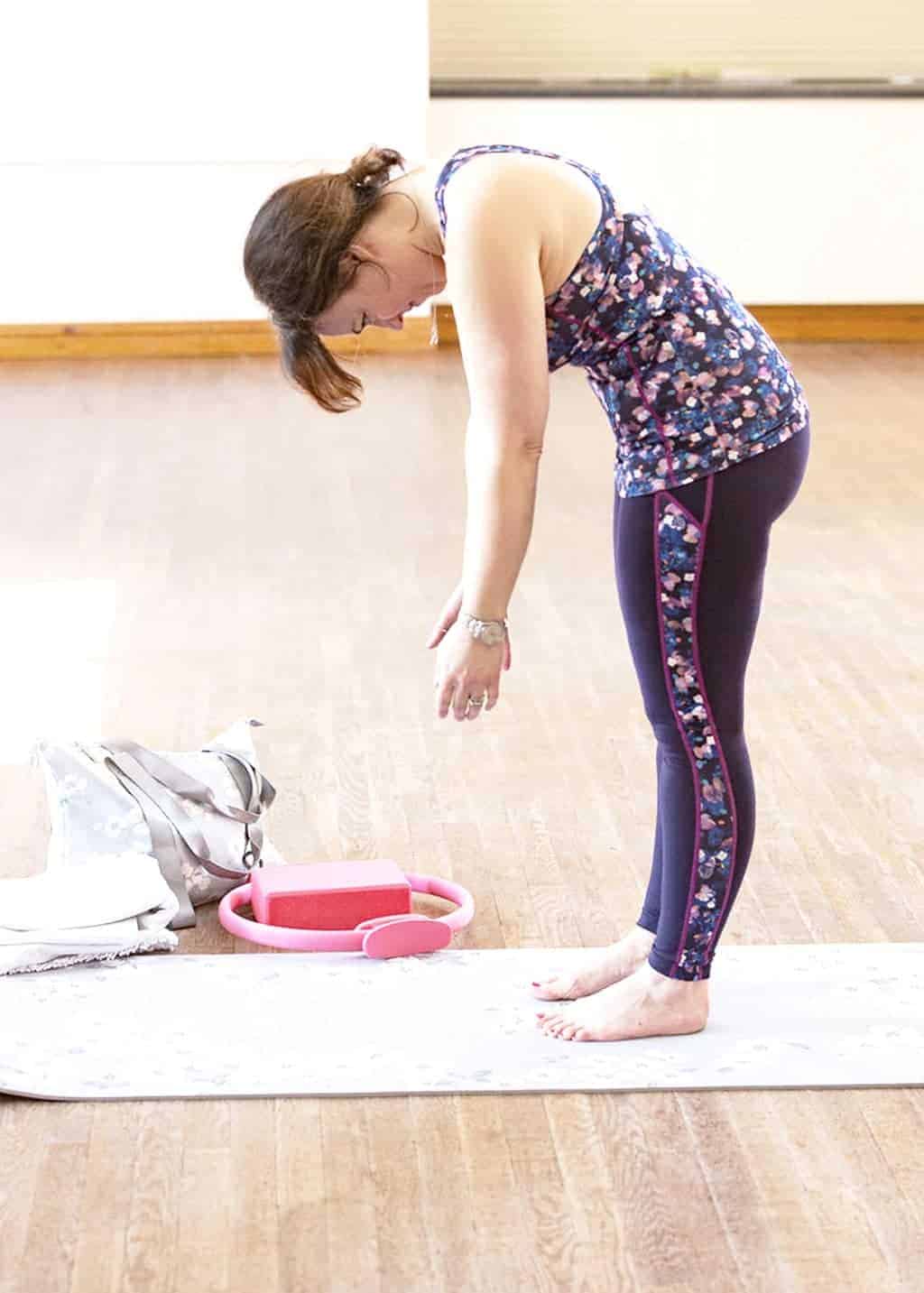 My Favourite 5 Pilates Moves — The Pilates Roll Down — Position 2 — Inhale, tighten your pelvic muscles and pull in your tummy to engage your abdominal muscles. Then exhale, tuck under your chin (which will lengthen the back of the neck) and let your shoulders drop forward, as your start bending the upper back. Allow the arms to dangle (imagine that skeleton again!). As you work your way down towards the floor, keep soft in the knees — don't lock them — you can have a slight bend, which will take the pressure off your lower back. Roll your entire spine forward and down, one vertebra at a time.